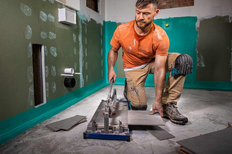 Carreleur travaillant avec une carrelette dans une salle de bains