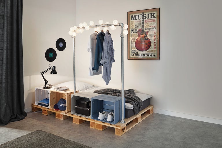 Chambre avec lit en palettes Europe, portant à vêtements avec lampes et éléments décoratifs