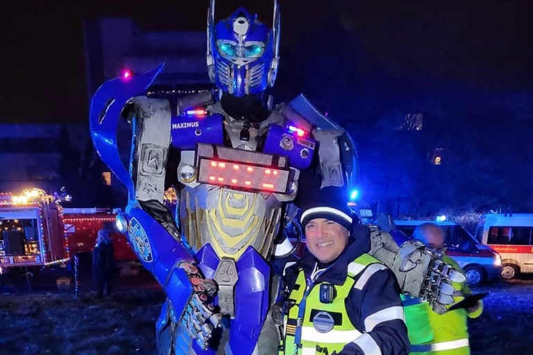 Person in Transformer-Kostüm mit Rettungskräften und Einsatzfahrzeugen im Hintergrund