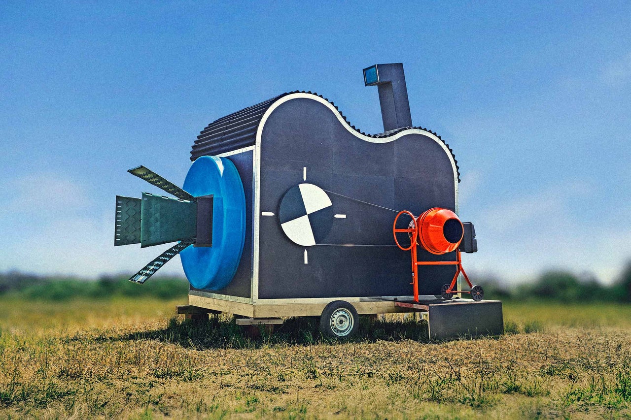 Sculpture faite de matériaux de construction et d une bétonnière sur une remorque en plein air.