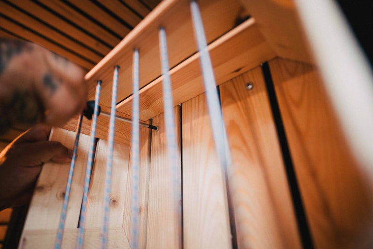 Nahaufnahme einer Person, die ein Holzregal mit einem Schraubenzieher montiert.