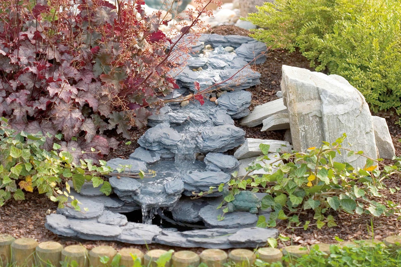 Aménagement paysager de jardin décoratif avec un ruisseau en ardoise et des plantes environnantes.
