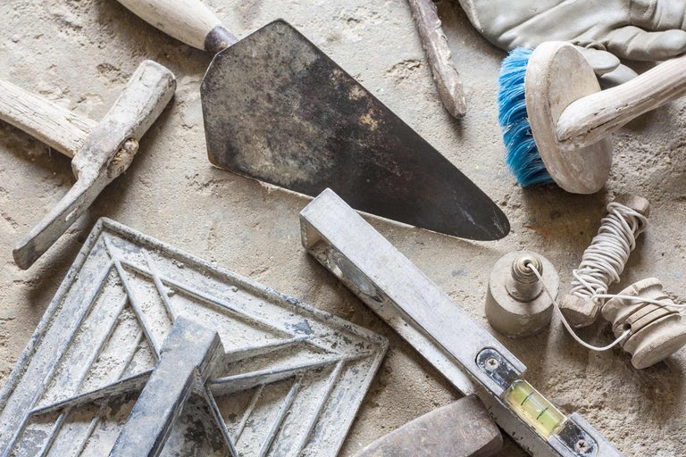 Divers outils de maçonnerie tels que truelle, règle, niveau à bulle, brosse à maçonner et cordeau de maçon