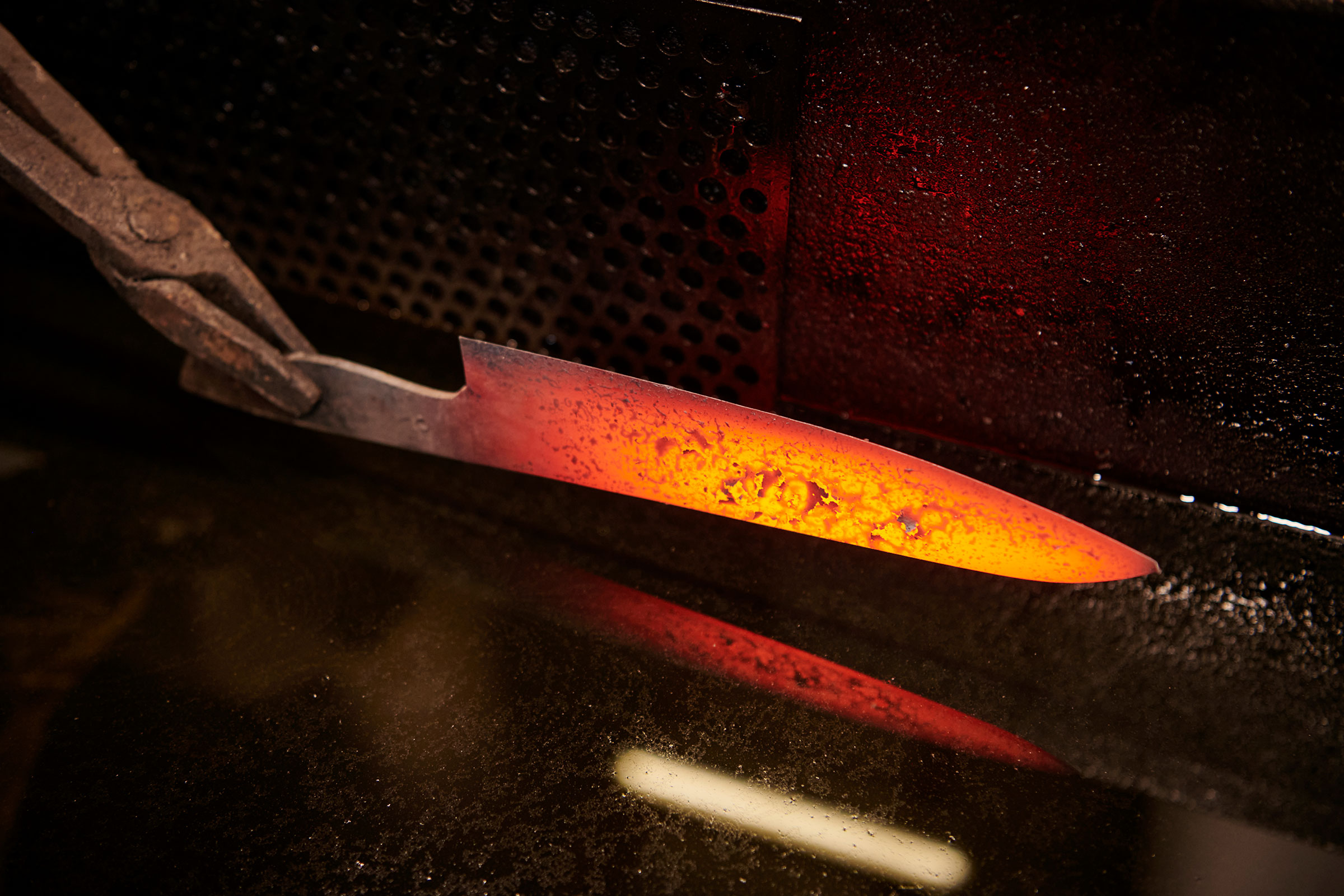 Glühendes Metallstück, gehalten von einer Zange