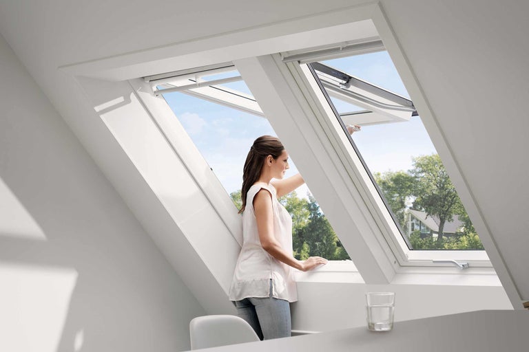 Frau öffnet Dachfenster in einem hellen Raum