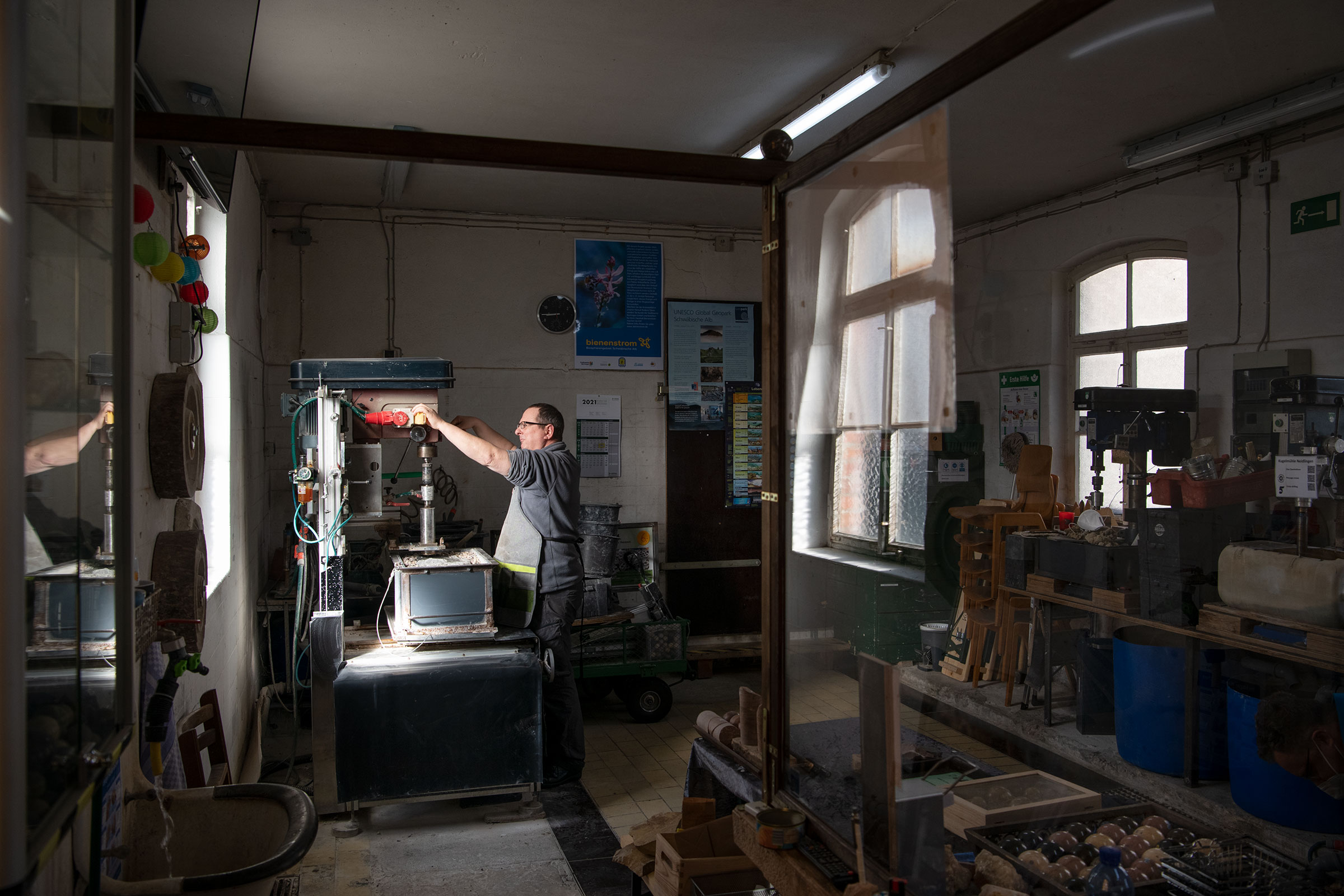 Werkstatt mit Werkzeugmaschinen und einer Person, die an einer Maschine arbeitet.