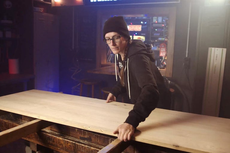 Frau hantiert mit Holzplatte in Werkstatt