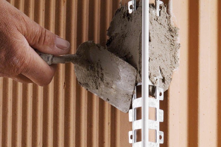 Application de mortier sur un mur à l'aide d'une truelle pour l'installation d'un collier de serrage.