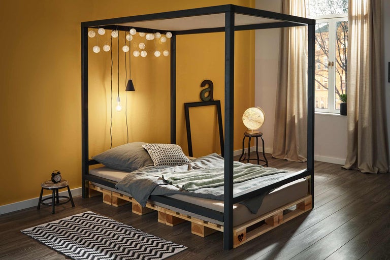 Chambre avec lit à baldaquin en palettes de bois et décoration