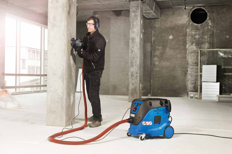 Un homme travaille avec une rainureuse à murs et un aspirateur industriel correspondant sur un chantier.