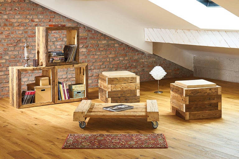 Salon avec étagère, table, tabourets, tapis et lampe dans les combles