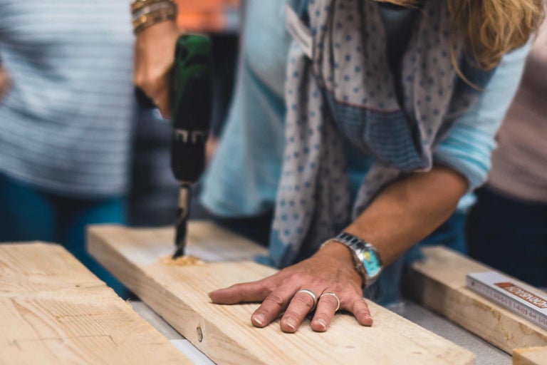 Une personne perce une planche de bois avec une perceuse sans fil.