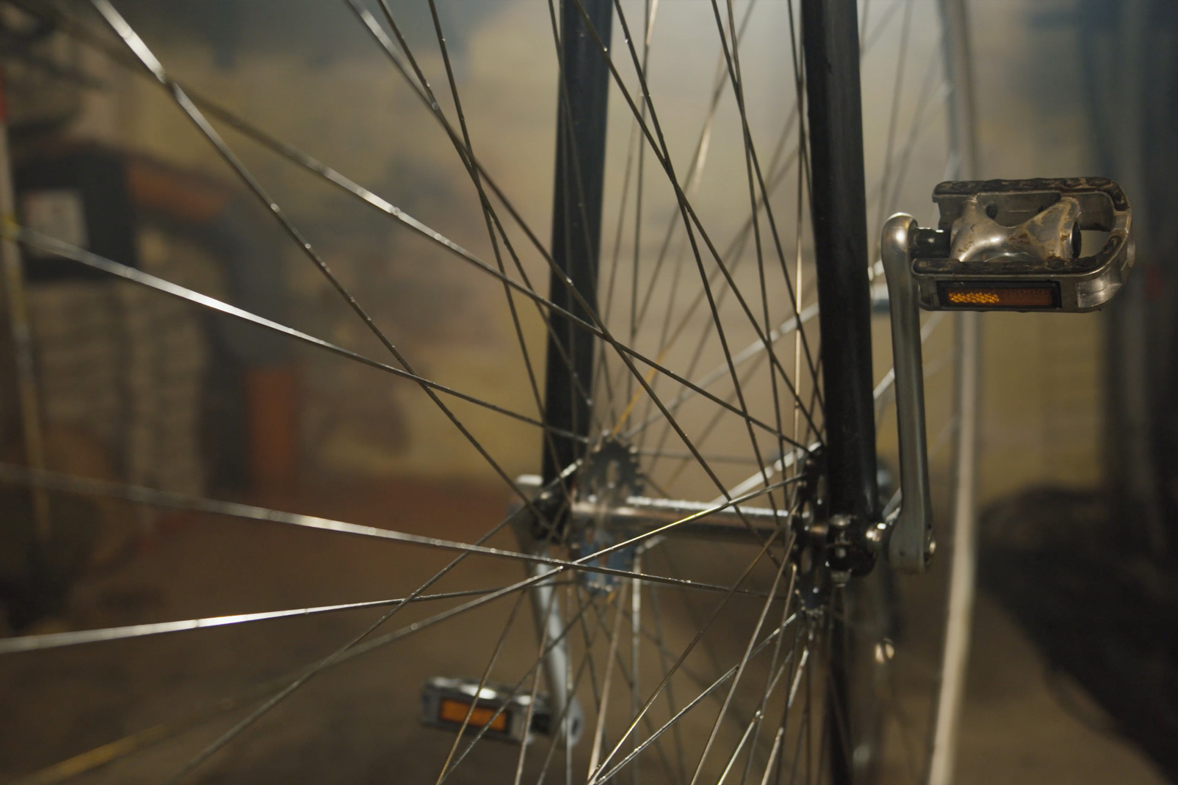 Nahaufnahme eines Fahrradreifens mit Speichen und Pedal