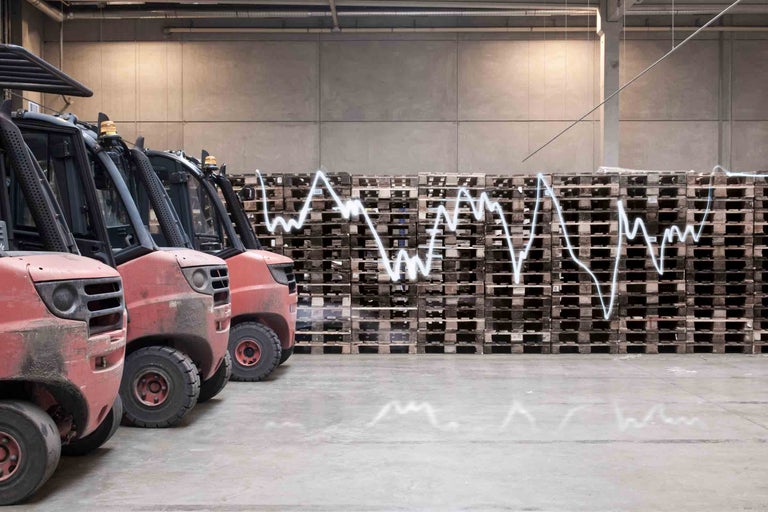 Rangée de chariots élévateurs devant une pile de palettes avec un diagramme illustrant les fluctuations de valeur