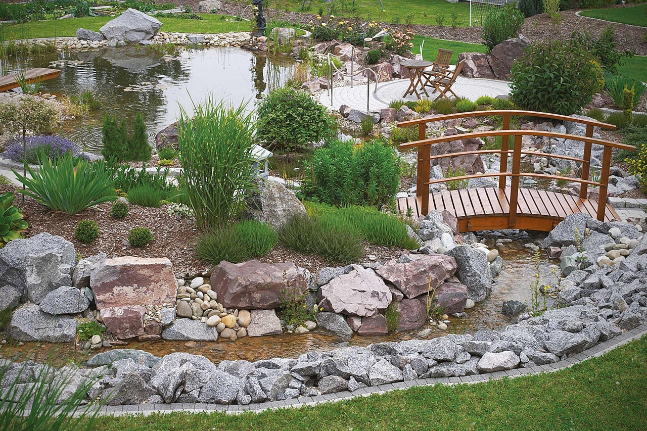 Bassin de jardin avec pont en bois, pierres et plantations