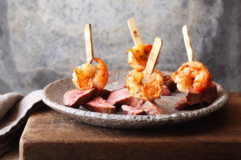 Teller mit gegrillten Garnelen am Spieß und Rindfleischstücken.