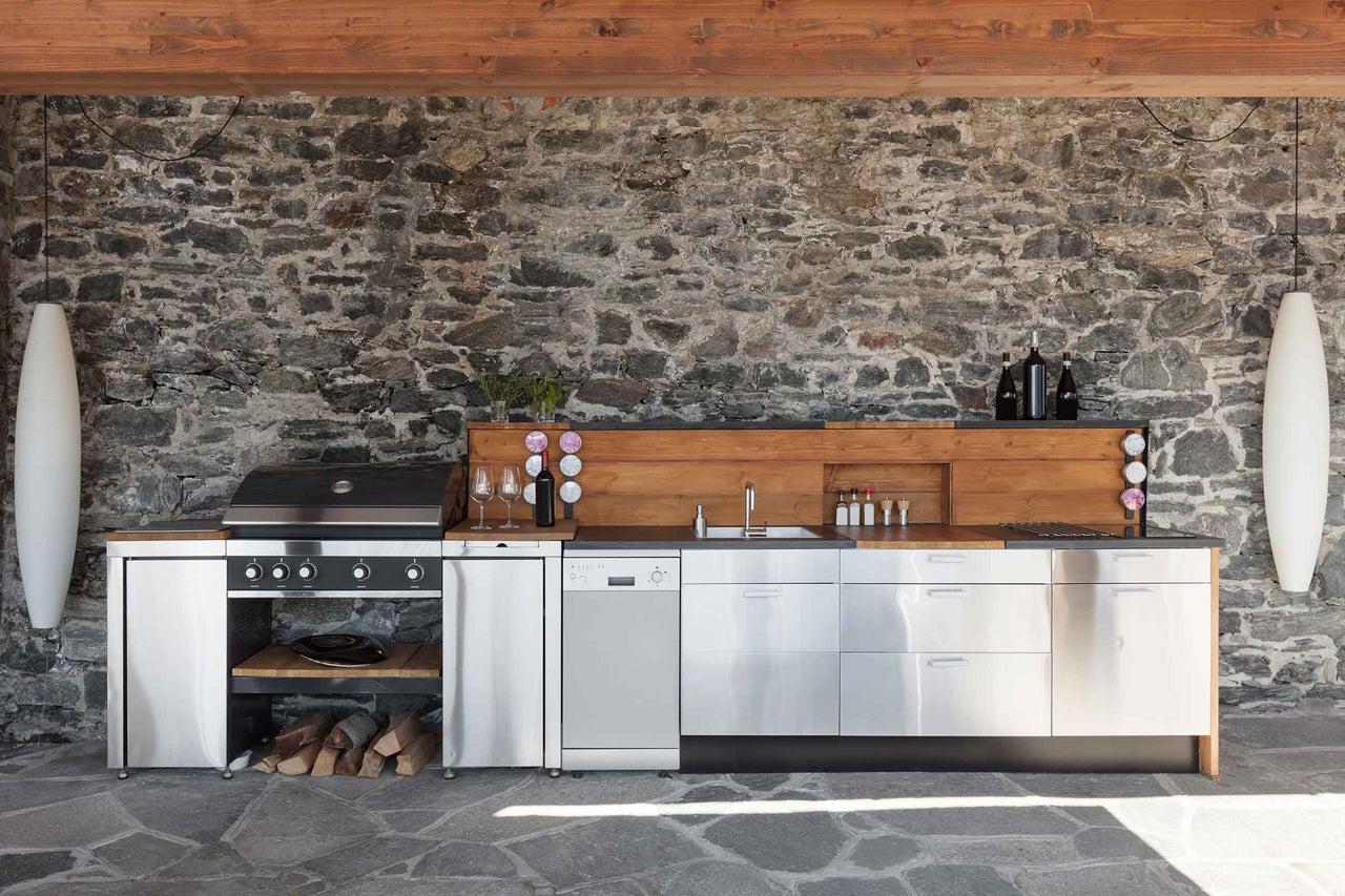 Aussenküche mit Grill, Spüle, Arbeitsflächen und Steinwand