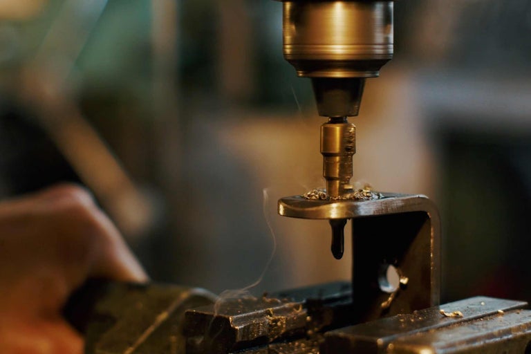 Mèche à métaux perçant une pièce métallique dans un étau.