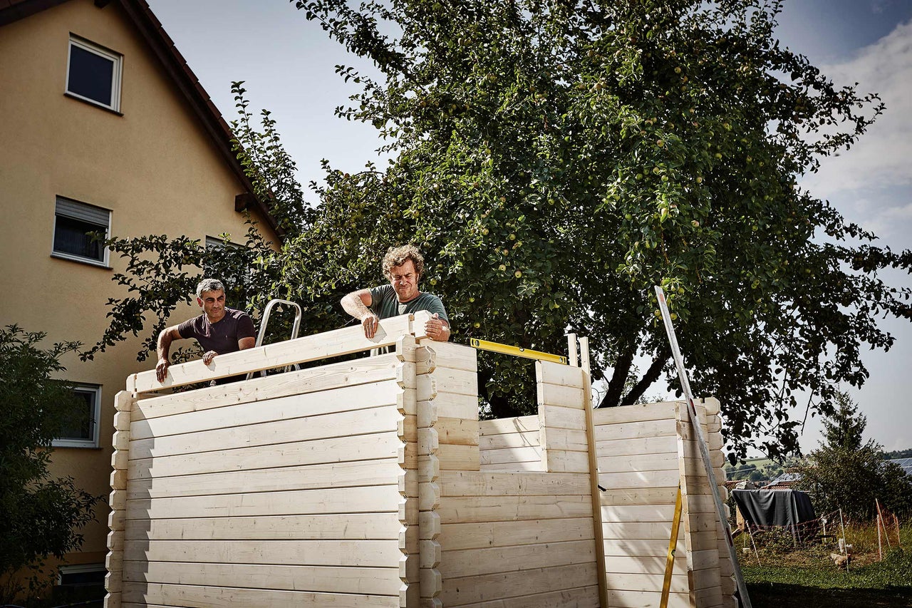 Deux personnes construisent une cabane de jardin en bois.
