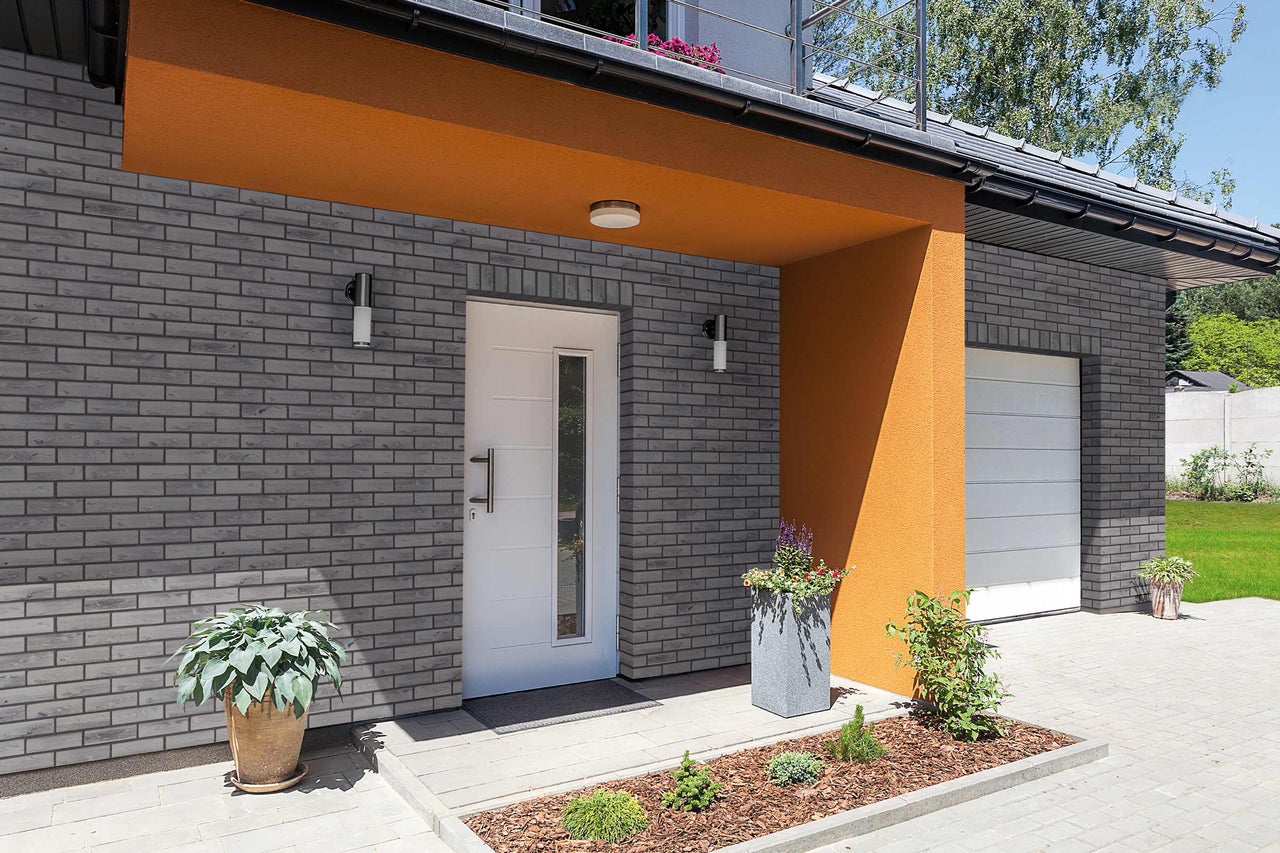 Vue extérieure d'une maison avec façade en briques, porte d'entrée et garage