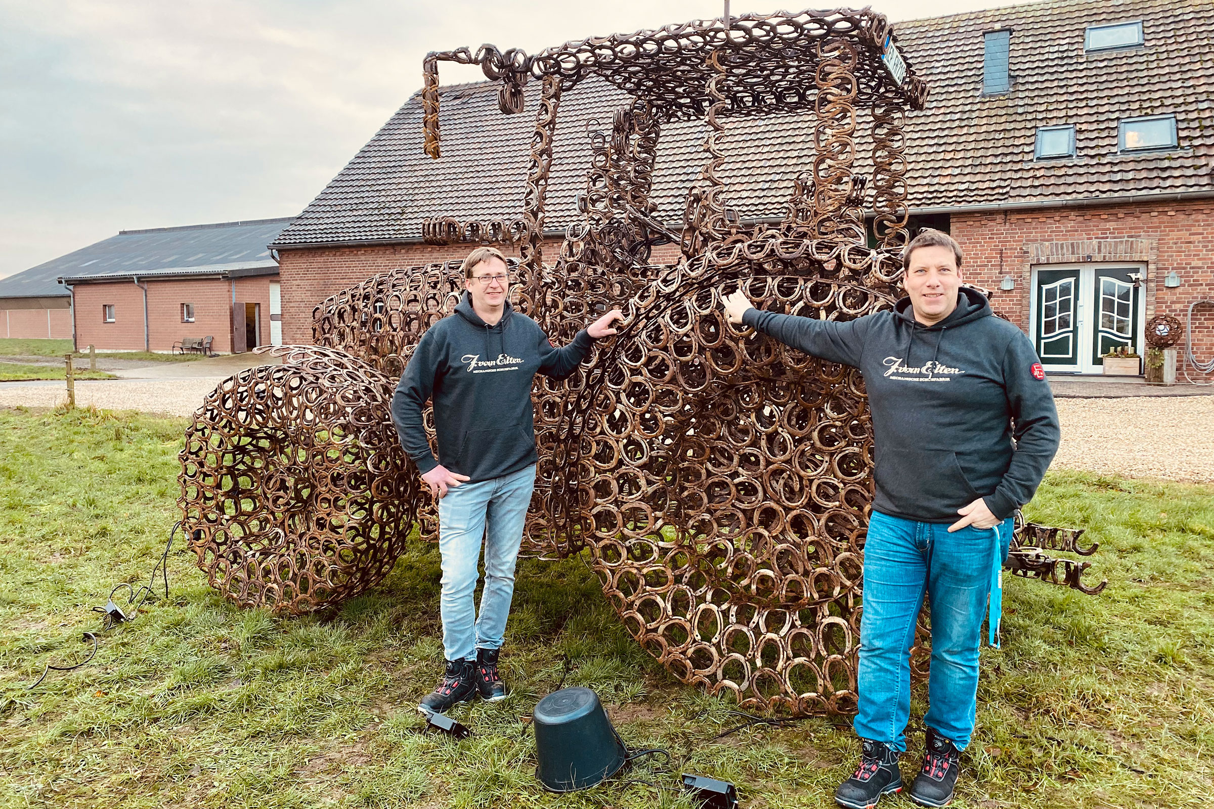 Skulptur eines Traktors aus Hufeisen mit zwei Personen