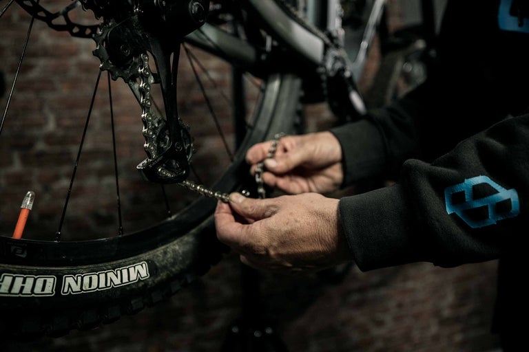 Nahaufnahme einer Person, die die Kette eines Fahrrads repariert