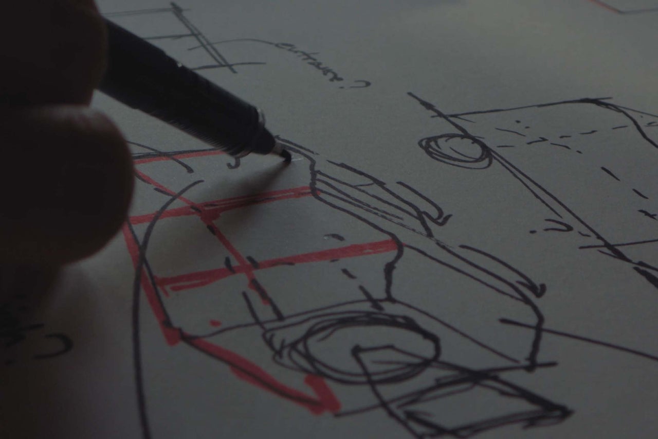 Main dessinant un croquis technique avec un stylo sur du papier