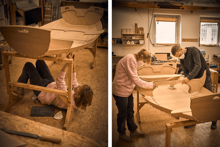 Deux personnes construisent un bateau en bois dans un atelier.