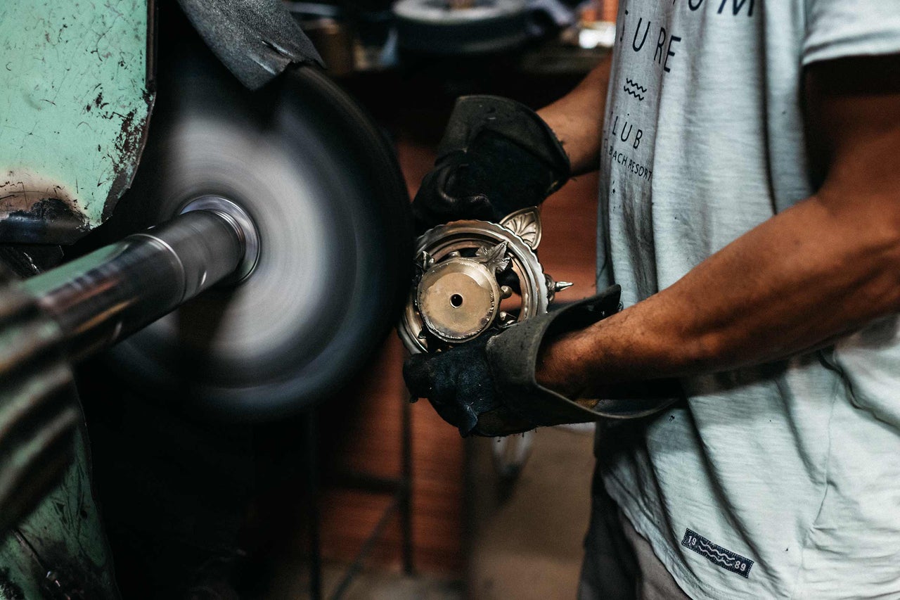 Une personne polit un objet métallique avec une polisseuse