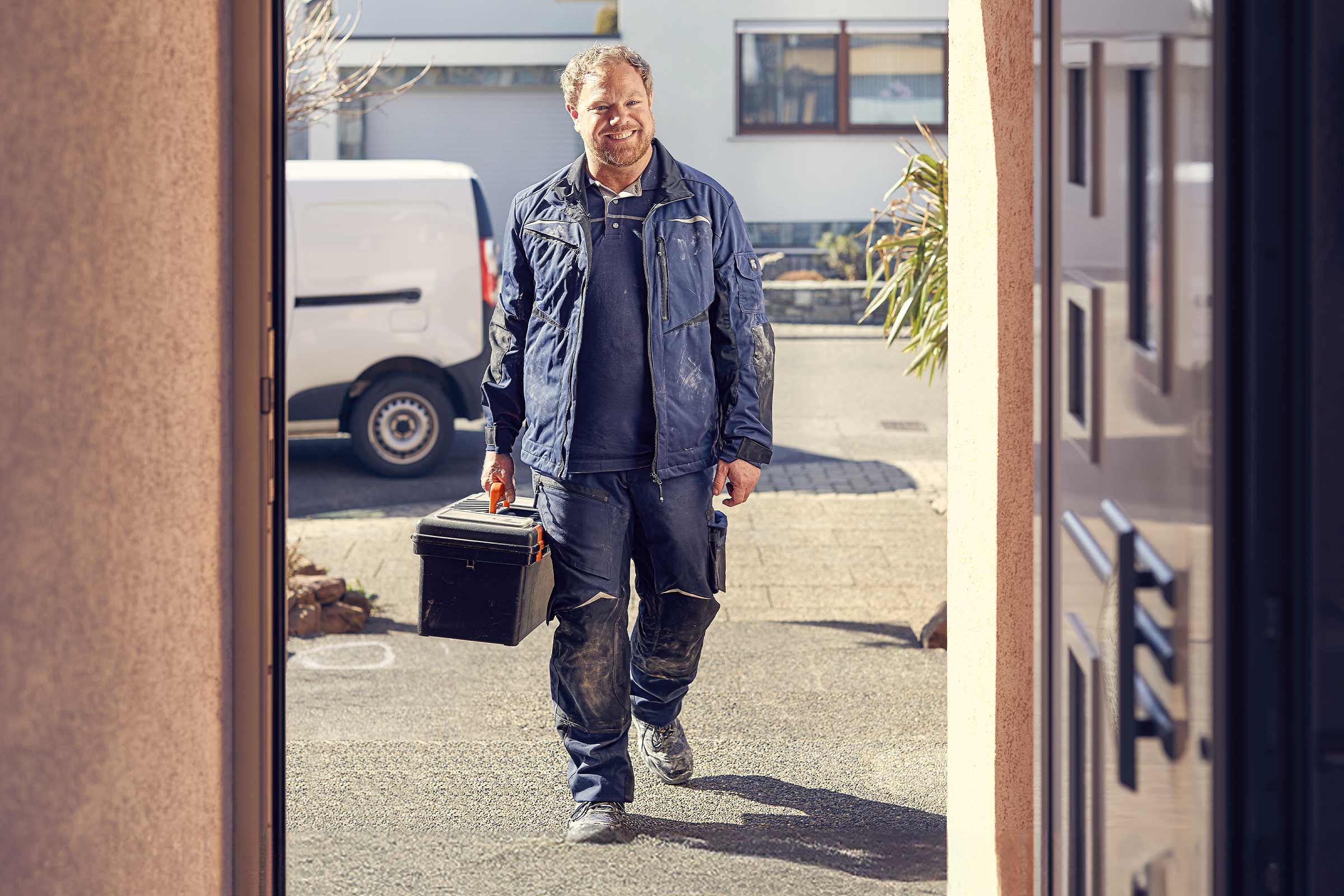 Artisan avec une boîte à outils devant un bâtiment