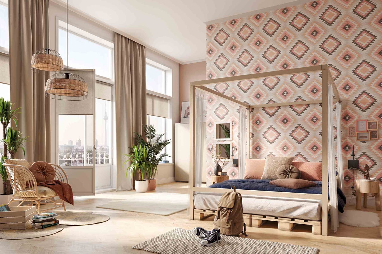 Chambre lumineuse avec lit à baldaquin, papier peint à motifs et meubles en rotin