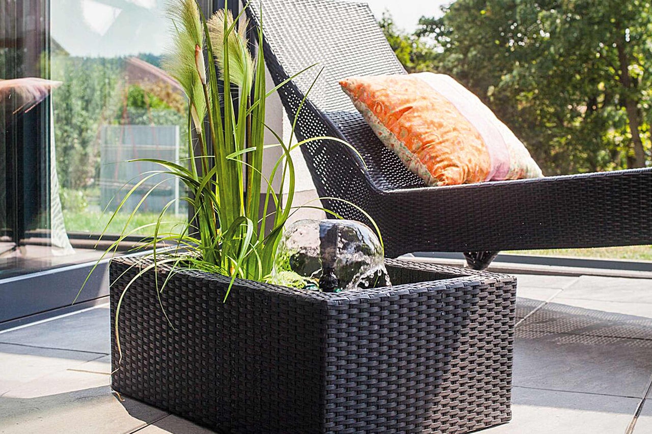 Jardin avec fontaine, plantes et chaise longue