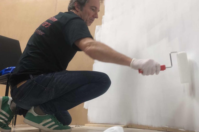 Ein Mann streicht eine Wand mit einer Farbwalze.