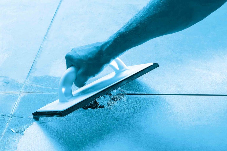 Une main tenant une taloche à joints pour jointoyer des carreaux