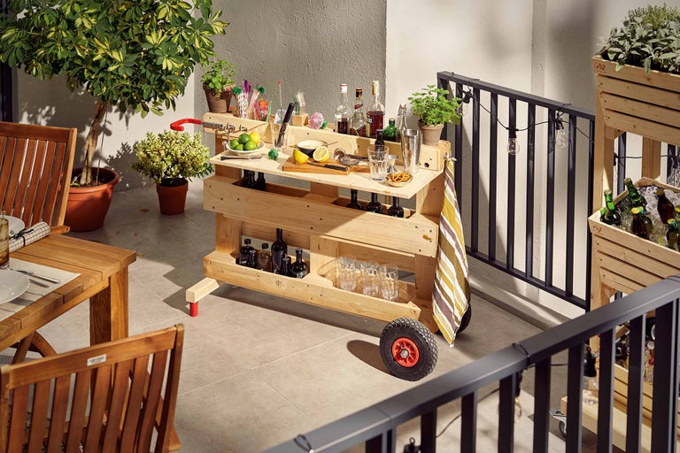 Aufnahme einer Holzbar auf einem Balkon, bestückt mit Getränken und Gläsern.