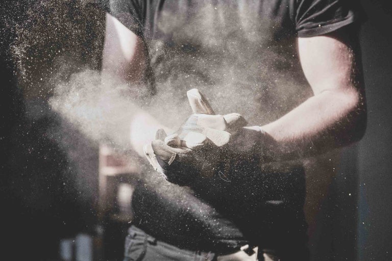 Eine Person mit Arbeitshandschuhen klopft Staub ab.