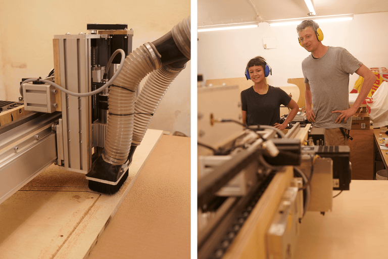 Fraiseuse CNC à commande numérique travaillant le bois. Deux personnes portent des protections auditives.