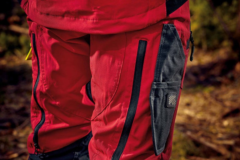 Gros plan d'un pantalon de travail rouge avec une poche zippée et une poche à outils