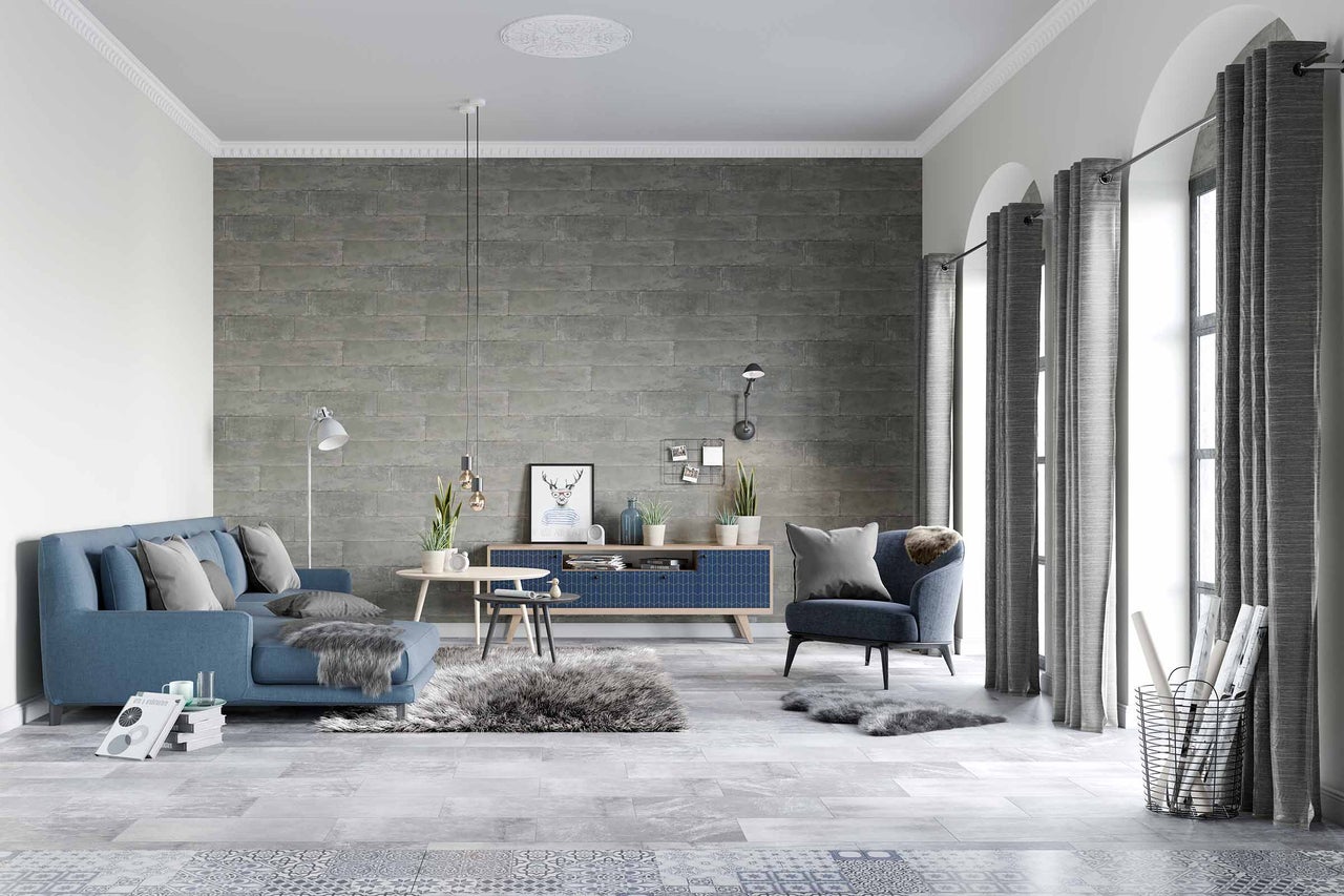 Salon avec canapé bleu, fauteuil, rideaux gris et mur à motifs
