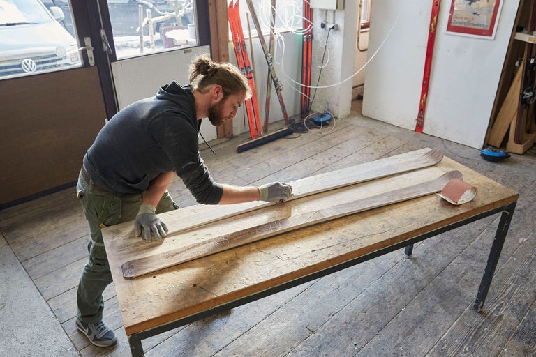 Mann schleift Holzskier auf einer Werkbank in einer Werkstatt