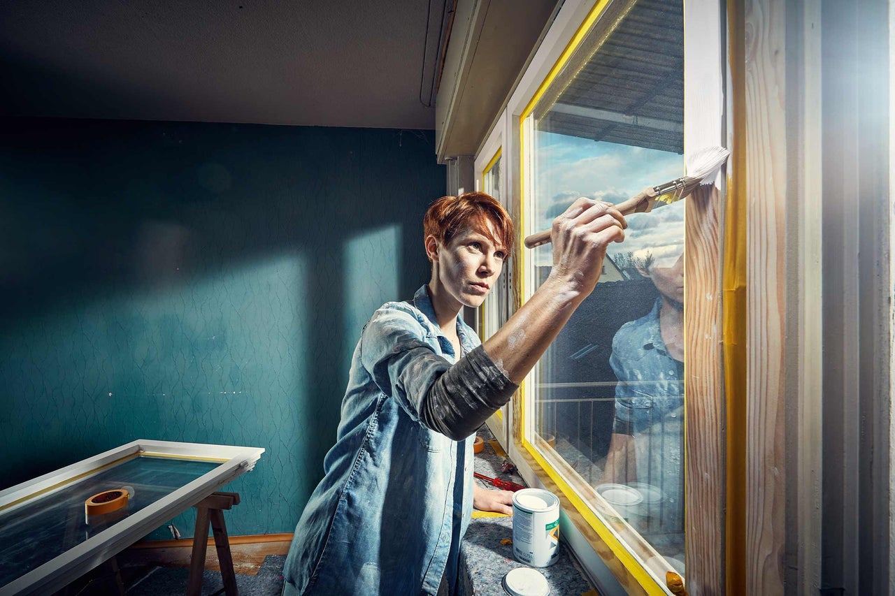 Une personne peint un cadre de fenêtre avec un pinceau et de la peinture.