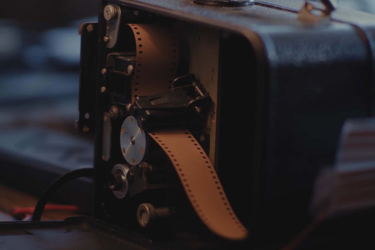 Gros plan d'un projecteur de film analogique avec une pellicule insérée à l'intérieur du boîtier ouvert.