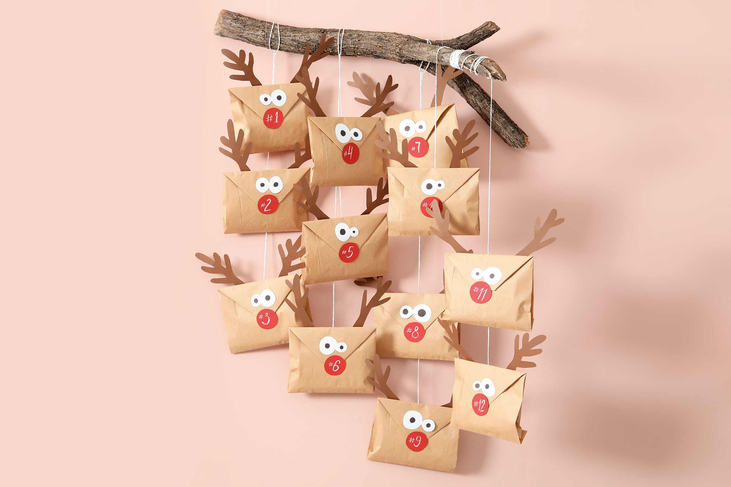 Calendrier de l'Avent DIY avec enveloppes en papier, bois de cerf en papier et une branche comme suspension
