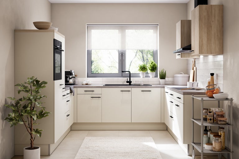 Cuisine intégrée moderne en forme de U avec façades beiges, poignées noires, éléments hauts en bois, four encastré et robinet noir.