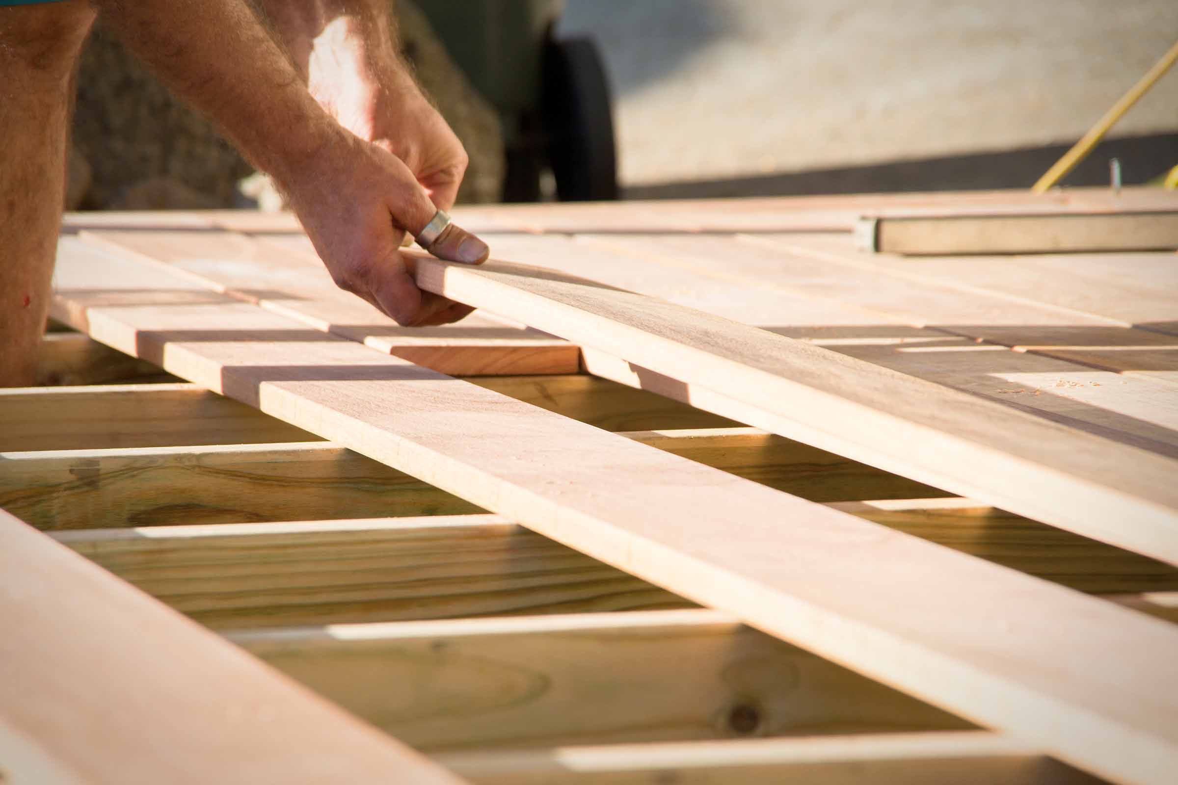 Mann verlegt Holzterrasse Dielen auf Unterkonstruktion