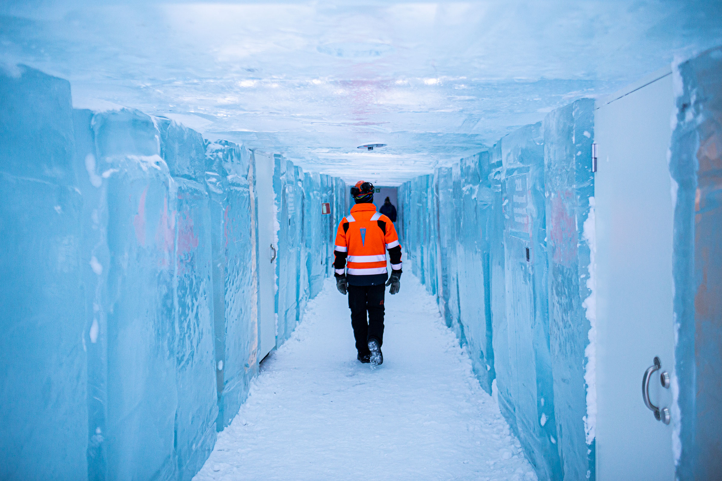 Person geht durch einen eisigen Tunnel mit Wänden aus Eisblöcken