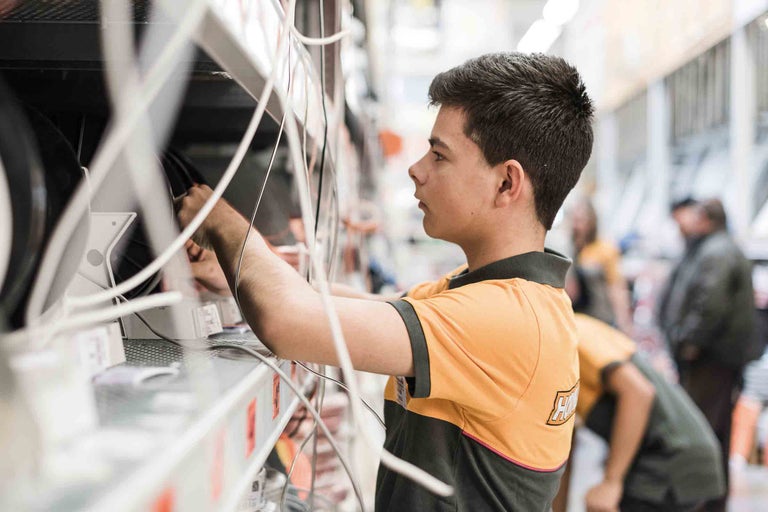 Ein Mitarbeiter von Hornbach ordnet Kabel im Regal.