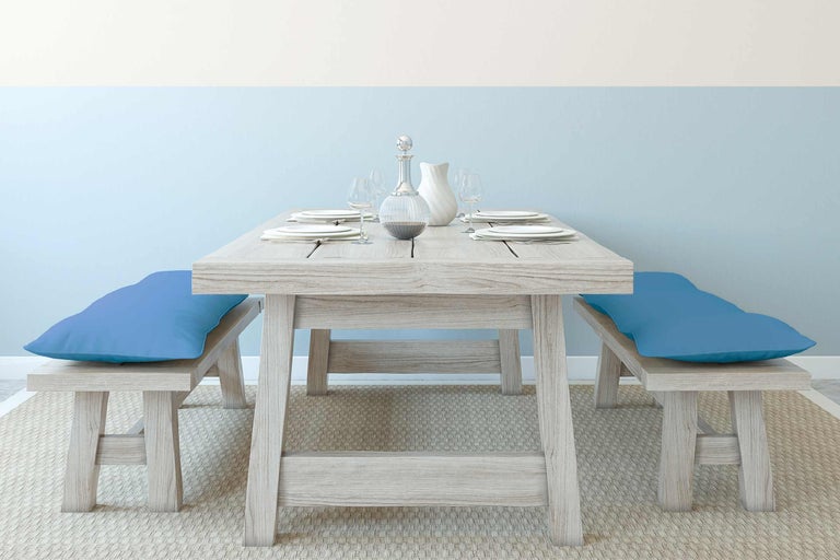 Ensemble de table à manger en bois avec bancs et coussins bleus sur un tapis