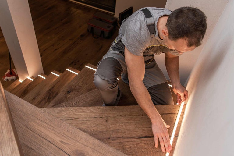 Artisan installant un éclairage LED sur un escalier en bois pour Hornbach