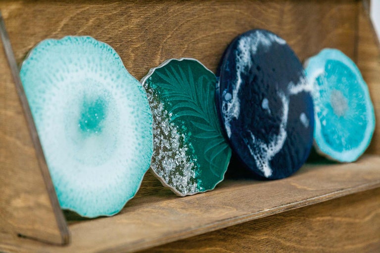 Dessous de verre décoratifs en résine synthétique sur une étagère en bois.